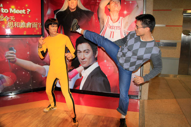 Tião luta contra estátua de cera de Bruce Lee, próximo à entrada do Madame Tussauds