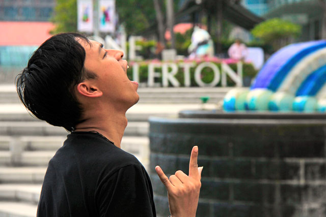 Visitante tenta uma foto em perspectiva forçada junto ao Merlion