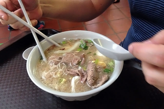 O Élcio toma sopa de fígado de porco, no Maxwell Road Hawker Centre